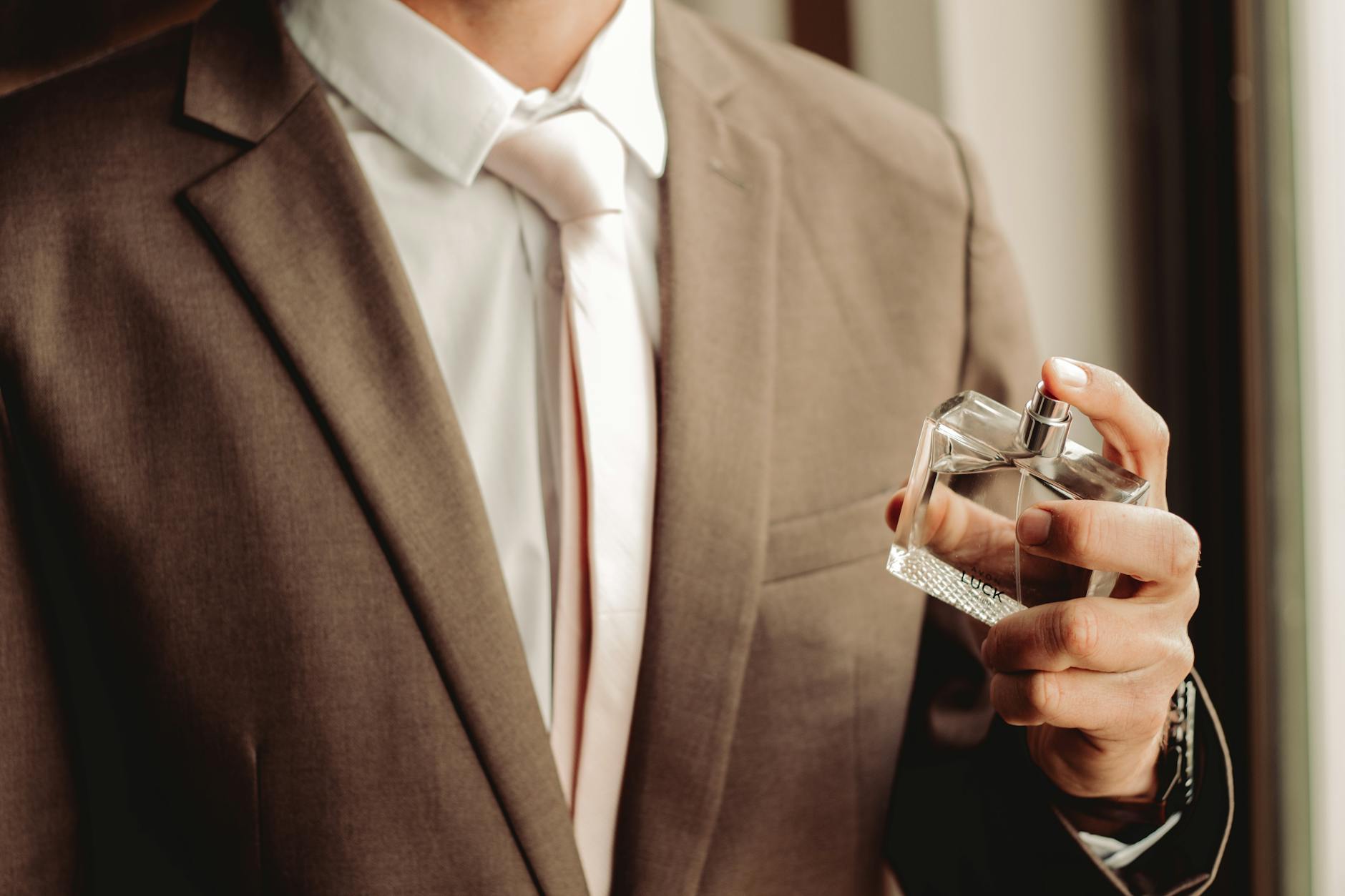 man wearing suit and necktie with perfume bottle